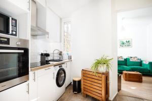 une cuisine avec un lave-linge et un canapé vert dans l'établissement Cosy appartement Paris 15, à Paris