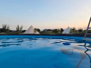 a pool of blue water with tents in the background at Kama Retreat in Kerpenyest