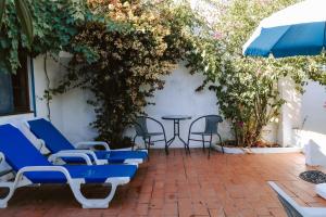 a patio with blue chairs and a table and vines at Jardim de Vénus in Vila de Frades