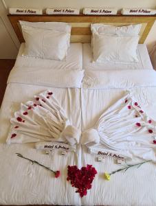 a bed with white sheets and red roses on it at Hotel Sai Palace in Satara