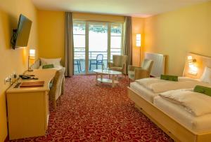 a hotel room with two beds and a table at Waldhaus am See inklusive MeineCardPlus in Willingen