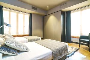 a bedroom with two beds and a chair and windows at Valencia Luxury - Boutique Paz in Valencia +10 photos