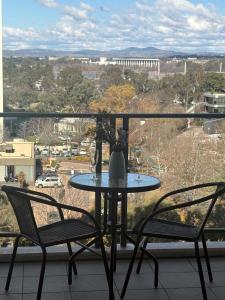 a table and chairs on a balcony with a view at The Metropolitan Apartments in Canberra
