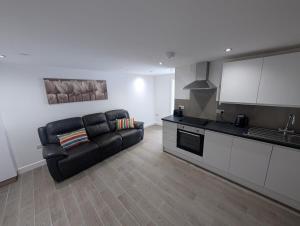 sala de estar con sofá negro en la cocina en City Escape – 1 Bedroom Flat in Swansea Centre, en Swansea