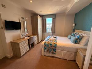 ein Schlafzimmer mit Bett, Schreibtisch und Fernseher in der Unterkunft Hotel Sheraton in Blackpool