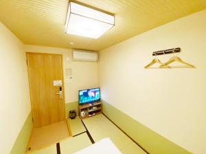 Cette chambre dispose d'une porte et d'une télévision murale. dans l'établissement Reina Building 4F / Vacation STAY 61776, à Tokushima