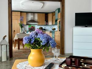 a yellow vase with purple flowers on a table in a kitchen at Ludwinas Pfingststube in Mastershausen