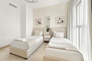 two beds in a white room with a window at Silkhaus Close to Ferrari World Abu Dhabi in Al Qurayyah +9 photos