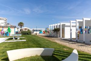 una panchina bianca sull'erba con un parco giochi di Hotel Numi a Rimini