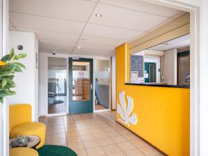 a lobby of a hospital with a yellow and blue wall at Premiere Classe Hotel Breda in Breda