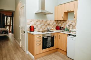 a kitchen with wooden cabinets and a stove top oven at Old Post Office in Talgarth