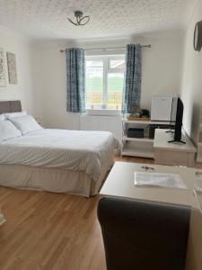 a bedroom with two beds and a desk with a computer at The Bungalow by SJP in Northamtonshire