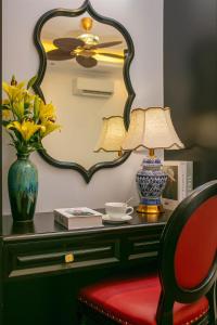 a table with a mirror and a vase with a lamp and a chair at Royal Hotel - Vinhomes Ocean Park 3 in Ðình Loan
