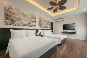 two beds in a hotel room with a ceiling fan at Royal Hotel - Vinhomes Ocean Park 3 in Ðình Loan