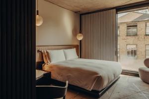 a bedroom with a bed and a window and a chair at Aethos London Shoreditch in London