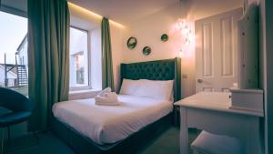 ニューキーにあるThe Feather's Hotel Newquayのベッド、机、窓のある寝室