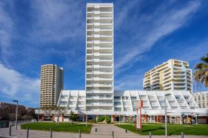 a tall white building in front of two tall buildings at Charming Flat with Balcony - Portimão by HostWise in Portimão