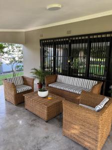 a patio with wicker couches and a coffee table at 47 Gem Holiday House in Lilongwe
