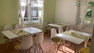 a group of tables and chairs in a room with windows at Manyi Villa in Băile Tuşnad