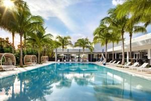 a swimming pool with palm trees and chairs at Le Meridien Dania Beach at Fort Lauderdale Airport in Dania Beach