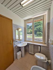 a bathroom with a sink and a toilet and two windows at Hotel Roccaporena & Margherita in Roccaporena