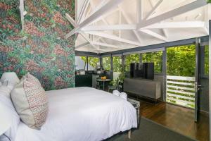 una camera da letto con un letto bianco e una tv di Forest Loft Apartment a Knysna