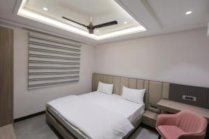a bedroom with a white bed and a pink chair at Hotel Vintage Villas in New Delhi