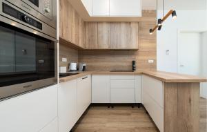 a kitchen with white cabinets and wooden walls at Stunning Home In Zaton in Zaton