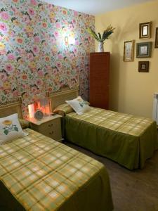 two beds in a hotel room with floral wallpaper at Casa Rural Abuela Carolina in Bermillo de Sayago