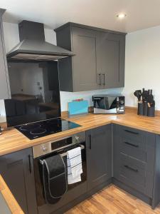 eine Küche mit grauen Schränken und einem Herd mit Backofen in der Unterkunft 2 bedroom country cottage in the Lake District in Penrith