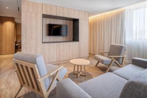 a living room with a couch and chairs and a tv at Moov Apartments Boavista in Porto