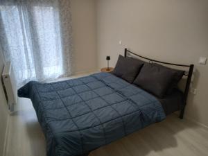 a bed with a blue comforter in a bedroom at Central apartment's in Trikala 2 in Tríkala