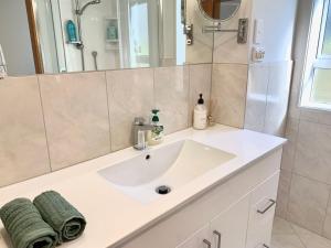 a bathroom with a sink and a mirror at Castor Bay Coastal Escape Walk to Beach in Auckland +7 photos