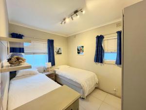 ケープタウンにあるNew! Green Point Room with Workstation & 8 min to Stadiumの青いカーテンが備わる客室のベッド2台