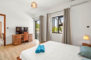 a bedroom with a bed with blue slippers on it at L'écrin de la Preneuse, villa avec piscine privée proche de la plage in Rivière Noire +22 photos
