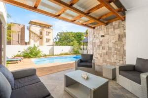 a patio with furniture and a swimming pool at L'écrin de la Preneuse, villa avec piscine privée proche de la plage in Rivière Noire