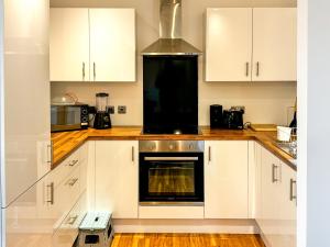 a kitchen with white cabinets and an oven at Flat in Greater manchester in Manchester
