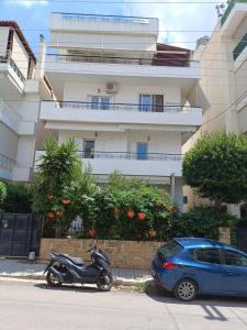 a scooter and a blue car parked in front of a building at Maria Cozy Getaway in Glyfada in Athens +15 photos