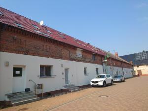a white car parked next to a brick building at Apartment 5 Zum Kuhstall Heinrichsberg - Magdeburg in Niegripp