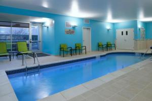 东兰辛SpringHill Suites by Marriott East Lansing University Area, Lansing Area的一个带绿色桌椅的游泳池
