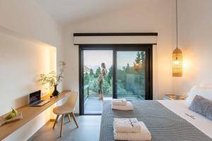 a bedroom with a bed and a desk and a woman on the balcony at Vasiliki Houses in Vasiliki