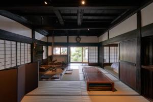a room with a table and a room with windows at Restored Kominka with Irori & Japanese Gardens in Okaya