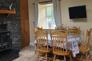 a dining room with a table and chairs and a television at Colleen Bawn Cottage Gap Of Dunloe Kerry in Killarney