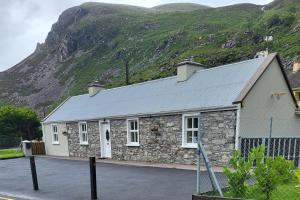 a stone building with a mountain in the background at Colleen Bawn Cottage Gap Of Dunloe Kerry in Killarney