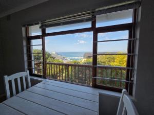 a balcony with a large window with a view of the ocean at Volgens Plan Family Holiday Home in Little Brak River in Reebok