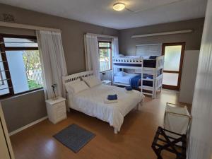 a bedroom with a bed and a bunk bed at Volgens Plan Family Holiday Home in Little Brak River in Reebok
