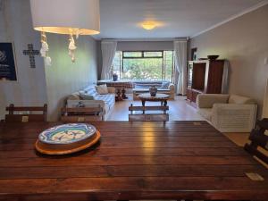 a living room with a wooden table and a living room at Volgens Plan Family Holiday Home in Little Brak River in Reebok