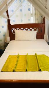 a bed with yellow sheets on top of it at parachichi house Bed and Breakfast in Arusha