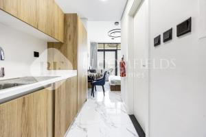 Bloomfields Canal View Stu In Al Maryah في أبوظبي: مطبخ بجدران بيضاء ودواليب خشبية