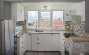 a kitchen with white cabinets and a large window at Apartment Luka in Makarska